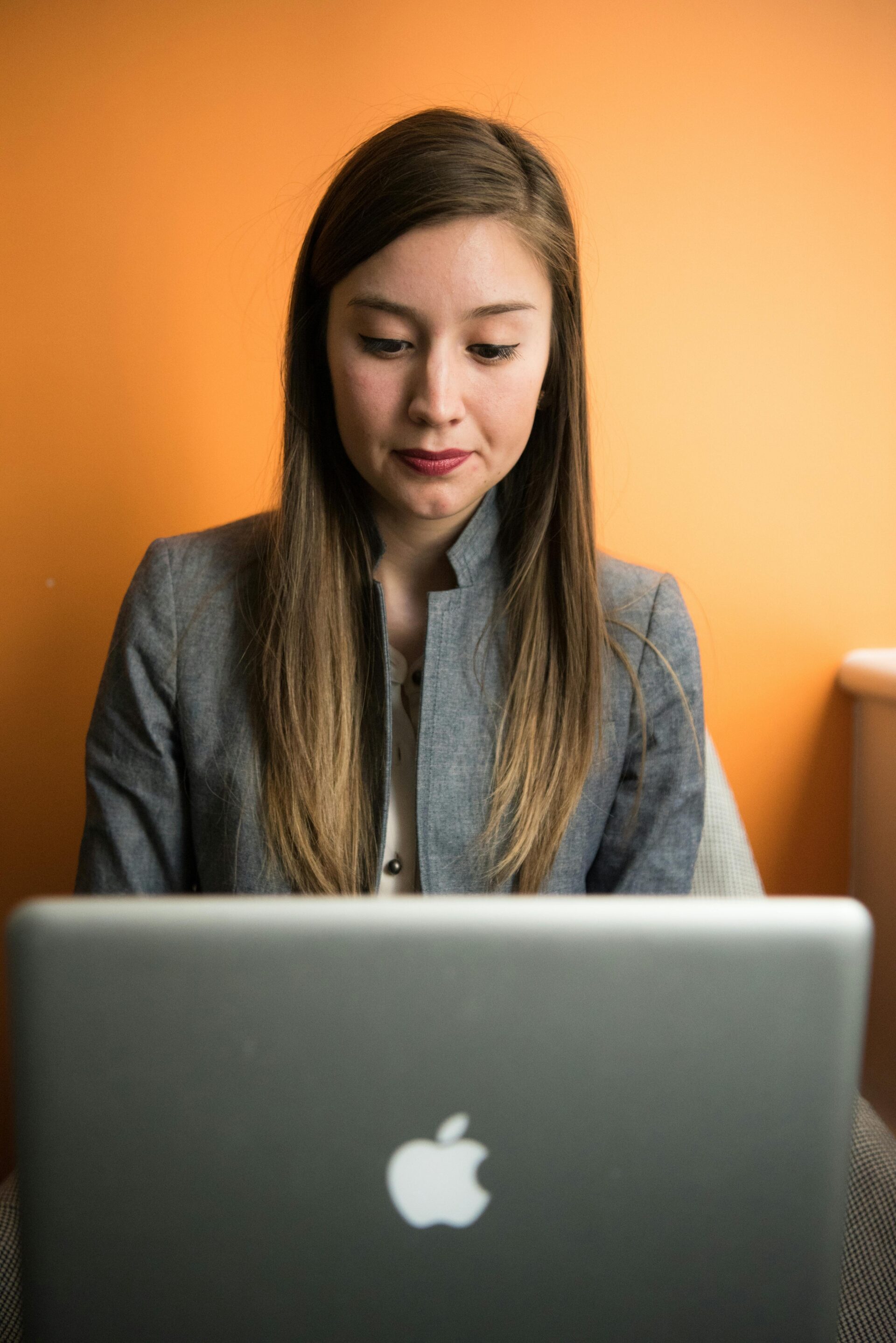 Focused young woman working on a laptop, representing the concept of AI Search Optimisation in a modern digital workspace.